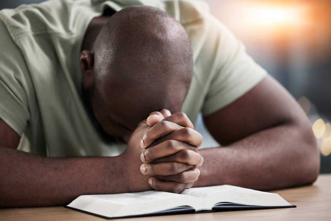 A man praying with a Bible at the table A man praying with a Bible at the table
