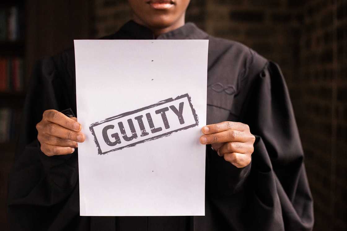 A judge holds a paper stamped "Guilty" in bold letters.