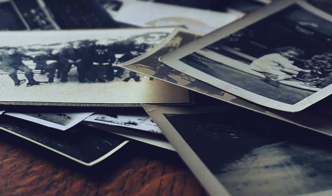 A collection of vintage black-and-white photographs scattered on a wooden surface. A collection of vintage black-and-white photographs scattered on a wooden surface.