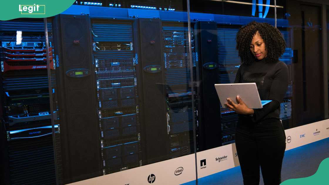 A software engineer standing beside server racks A software engineer standing beside server racks
