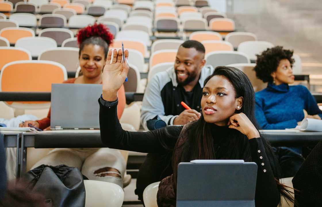 A female student raises her hand during a lecture. A female student raises her hand during a lecture.