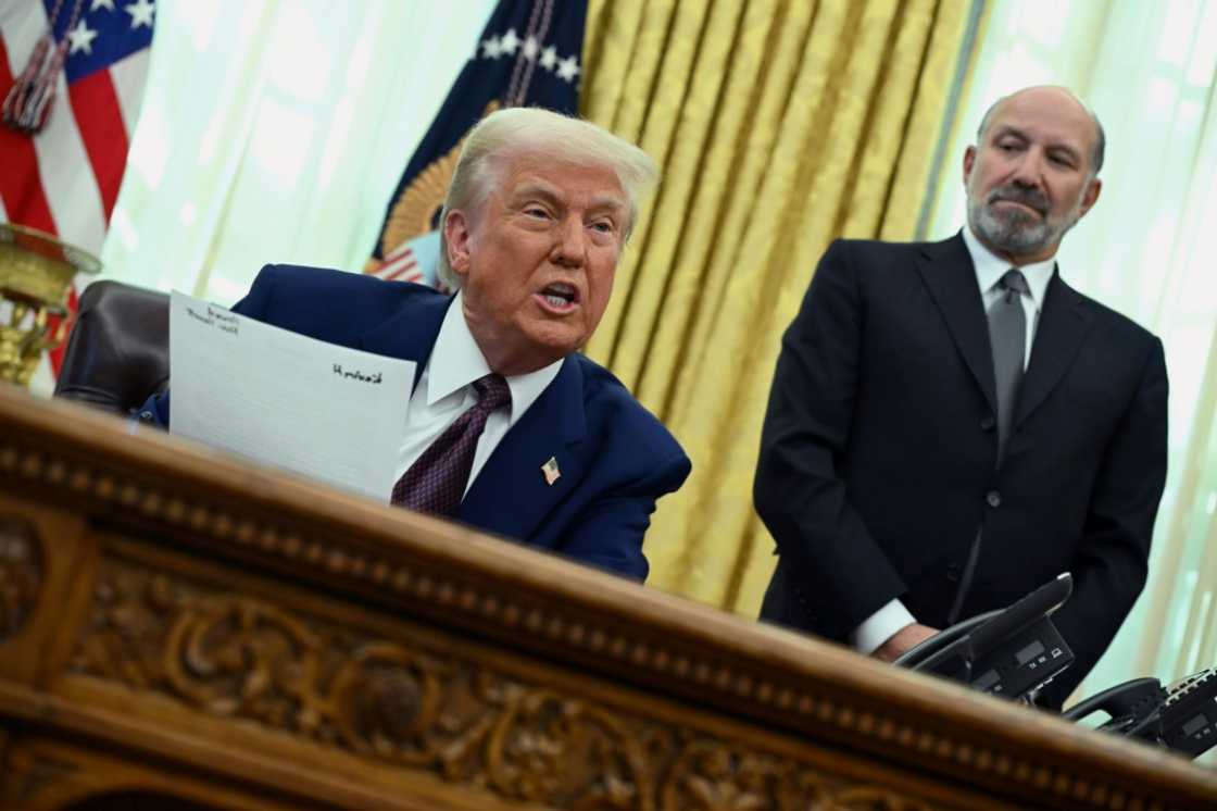 US President Donald Trump announces reciprocal tariffs from the White House Oval Office on February 13, 2025 as Howard Lutnick looks on