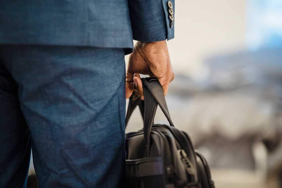 Man in a suit holding a black bag by his side. Man in a suit holding a black bag by his side.