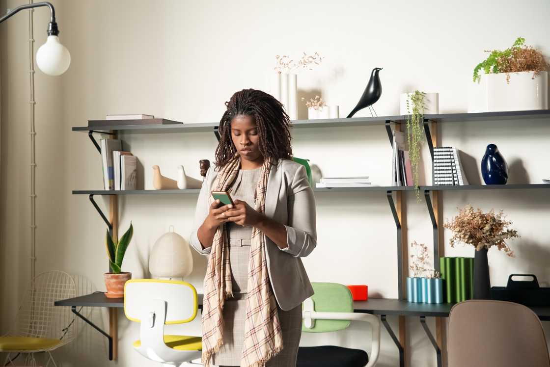 A woman in an office is using a smartphone
