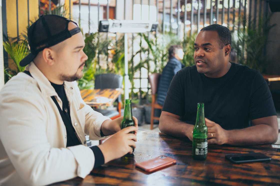 Two friends sit at a small café talking. Two friends sit at a small café talking.