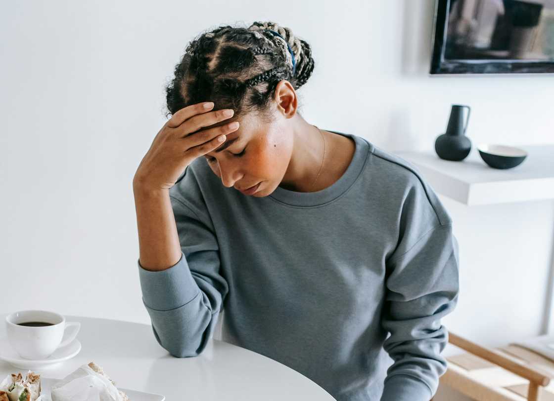 A distressed woman holds her head in the kitchen. A distressed woman holds her head in the kitchen.