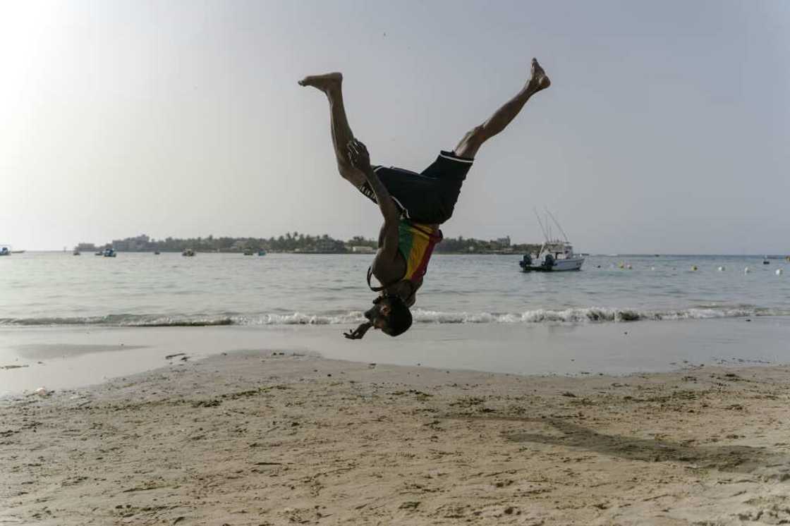 Malick, a 30-year-old acrobat from Guinea, trains on a Dakar beach Malick, a 30-year-old acrobat from Guinea, trains on a Dakar beach