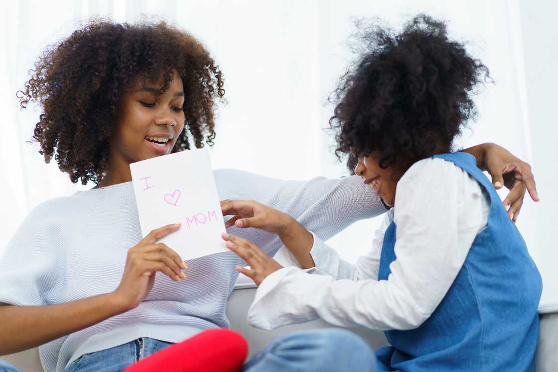 Child at home proudly showing a small “Goal Card” to her mother. Child at home proudly showing a small “Goal Card” to her mother.