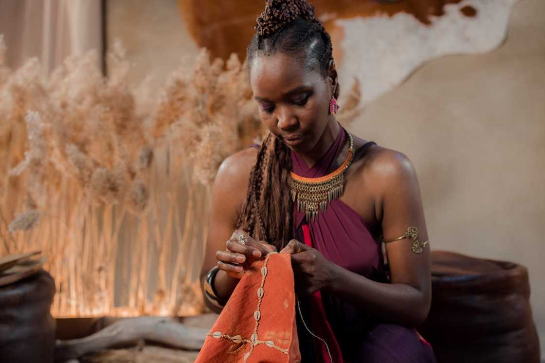 A woman sewing fabric by hand in a softly lit room. A woman sewing fabric by hand in a softly lit room.