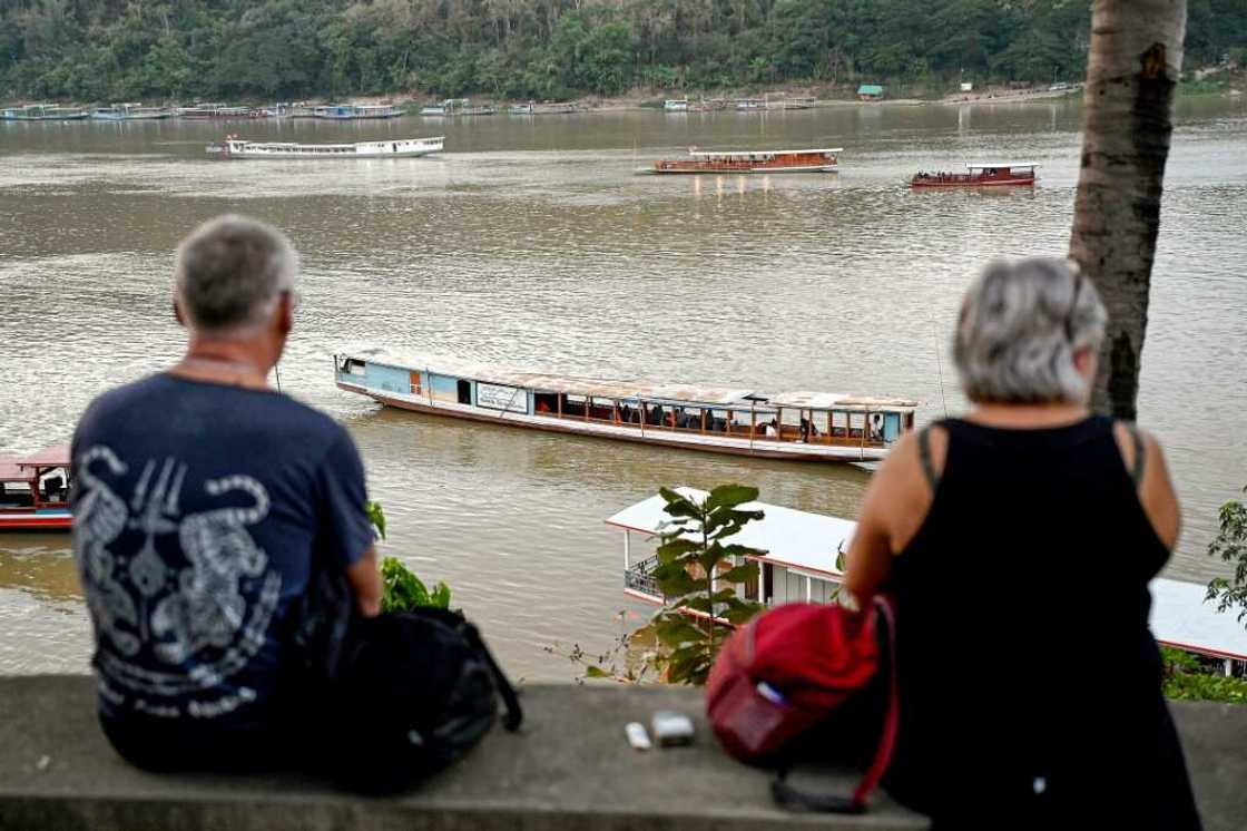 Tourists watch boats cruising on the Mekong river in Luang Prabang Tourists watch boats cruising on the Mekong river in Luang Prabang