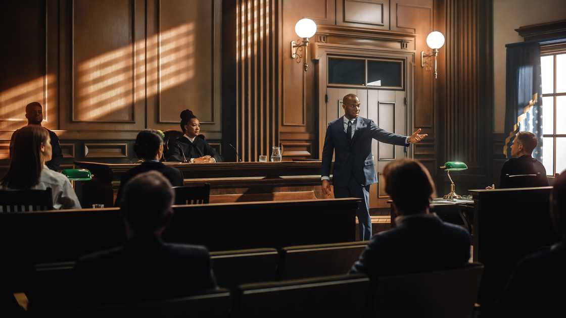 Courtroom scene with a lawyer in a blue suit addressing the judge. Courtroom scene with a lawyer in a blue suit addressing the judge.