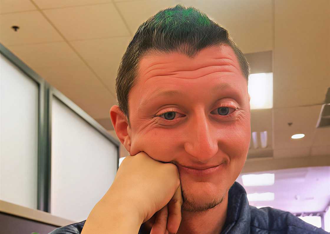 Daniel Larson holding his cheek as he takes a photo