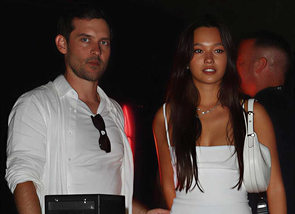 Tobey Maguire and Lily Chee walk on a path. Tobey Maguire and Lily Chee walk on a path.