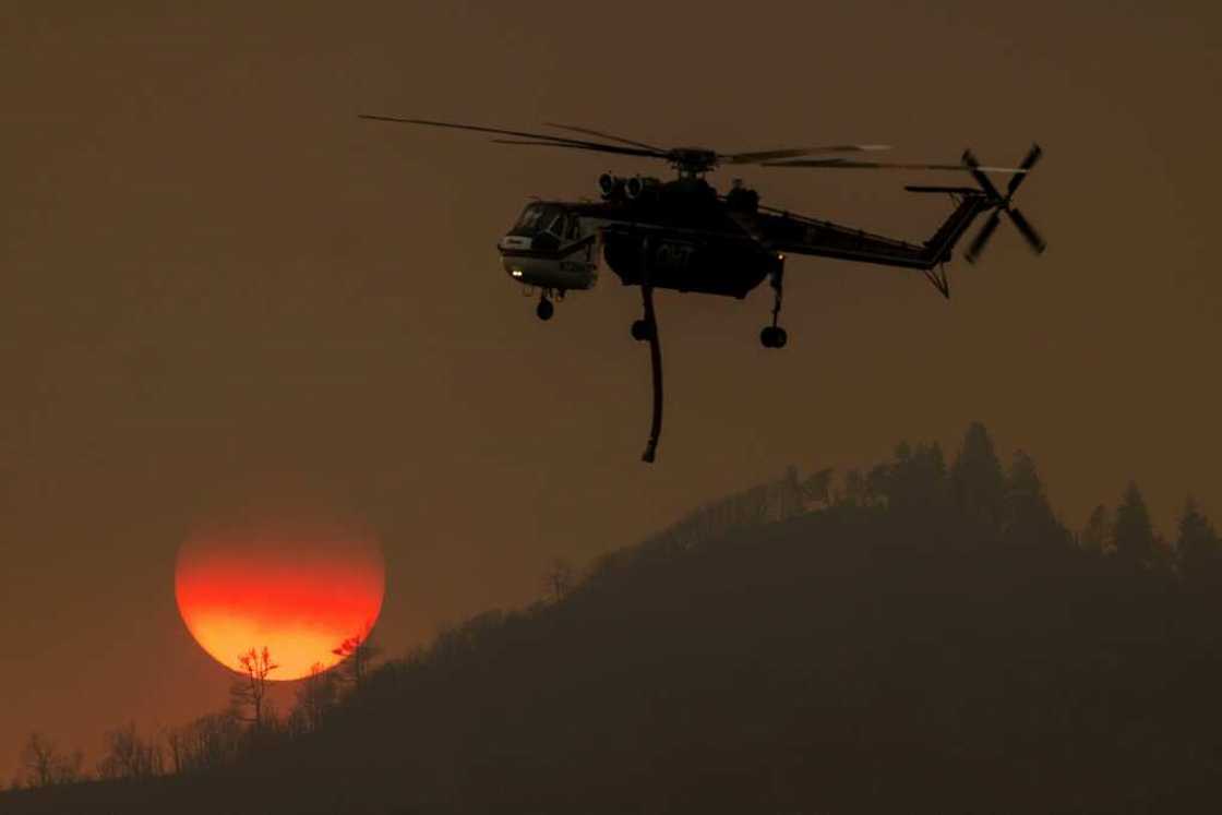 A firefighting helicopter passes the setting sun while fighting the Oak Fire near Mariposa, California A firefighting helicopter passes the setting sun while fighting the Oak Fire near Mariposa, California