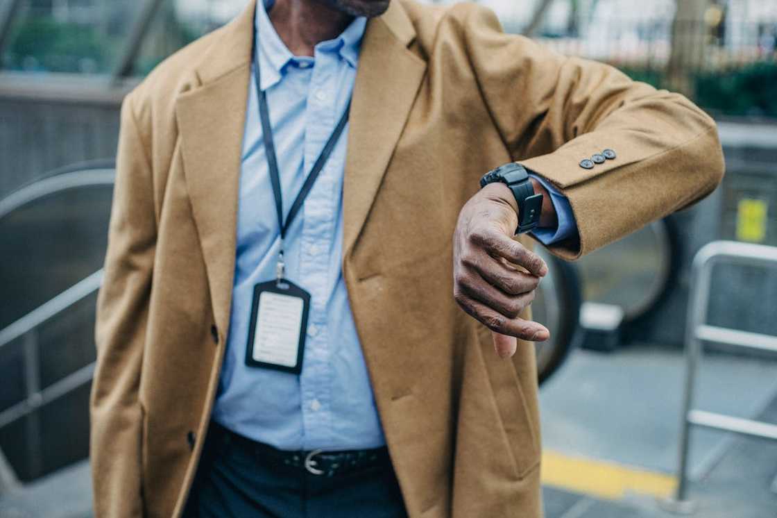 A man wearing a coat checks the time on his wristwatch outdoors. A man wearing a coat checks the time on his wristwatch outdoors.