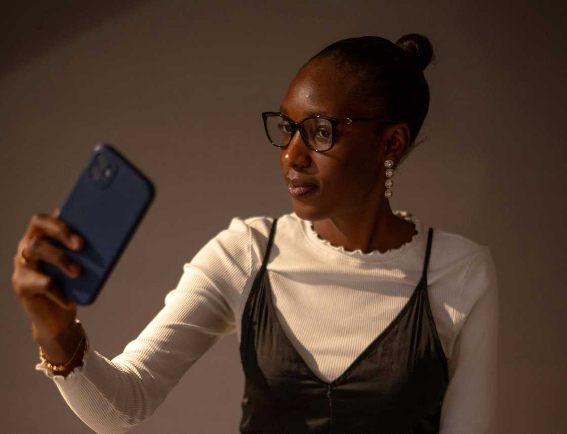 A woman in glasses taking a selfie with her phone