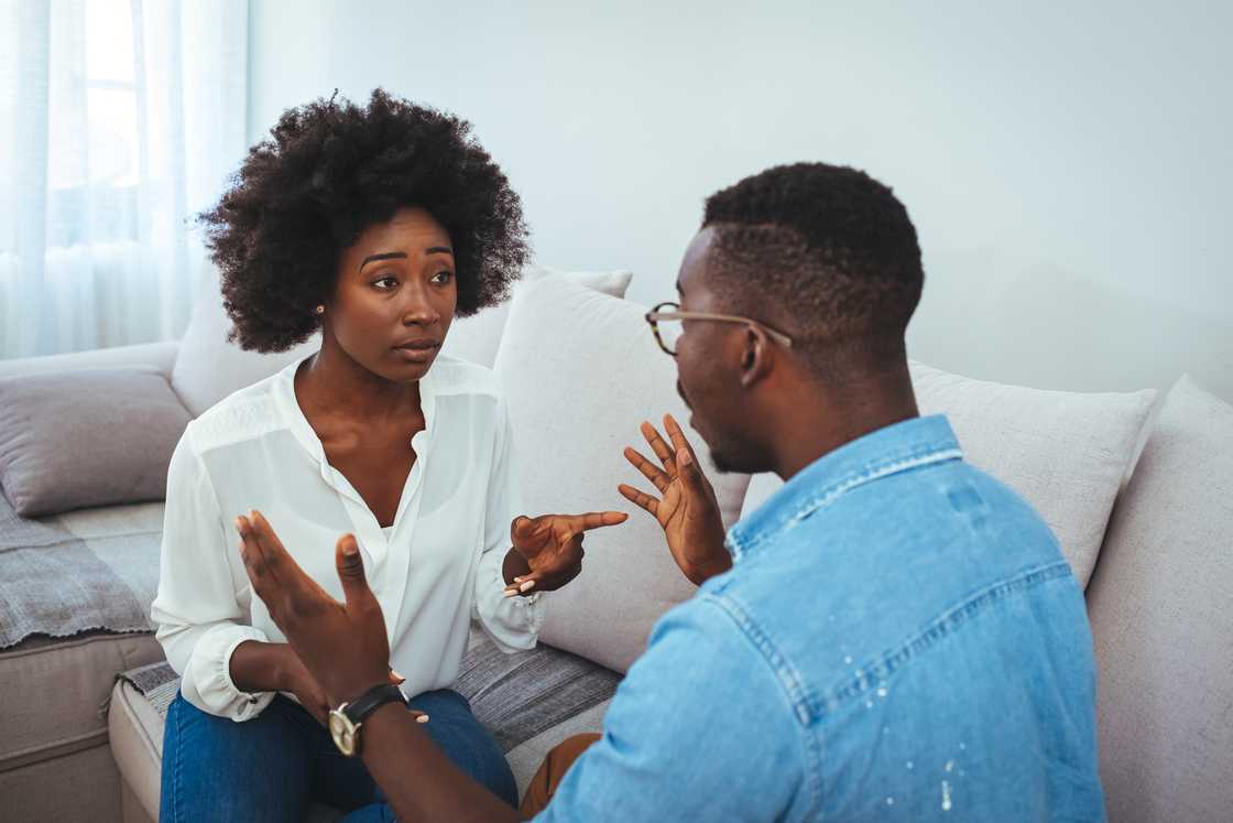 A young couple sitting on the couch having a family fight.