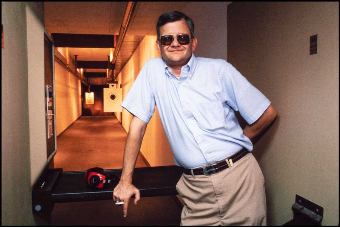 American author Tom Clancy poses in his home rifle range in 1990