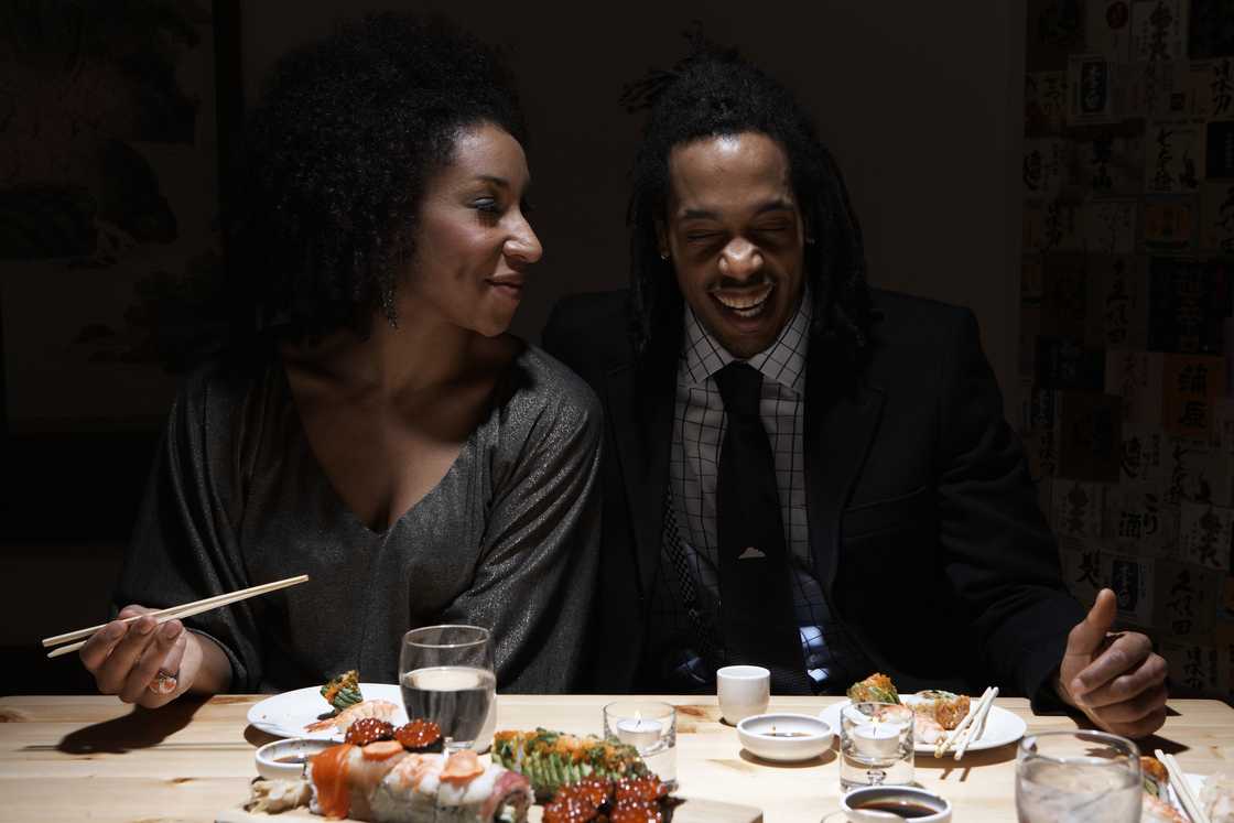 A young couple laughing together over dinner. A young couple laughing together over dinner.