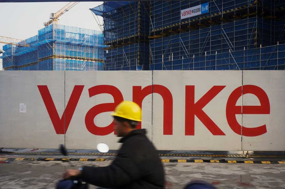 A worker drives past residential buildings under construction by Chinese real estate developer Vanke in Hangzhou in March 2024