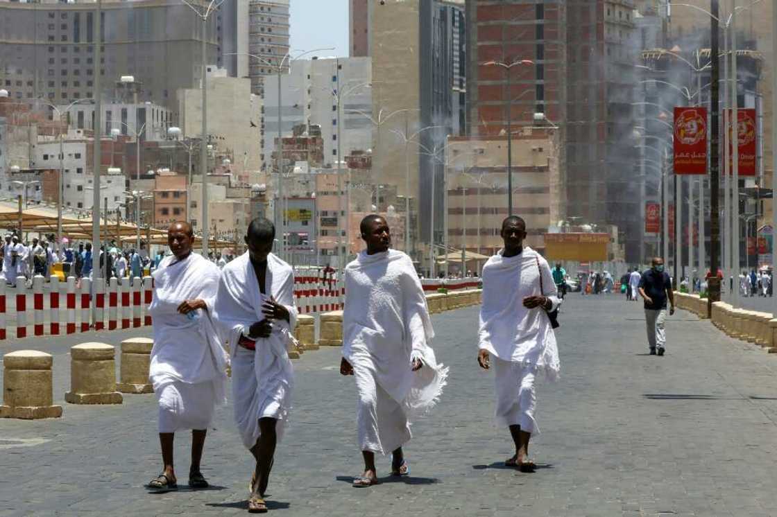 Pilgrims walk under mist sprayers Pilgrims walk under mist sprayers