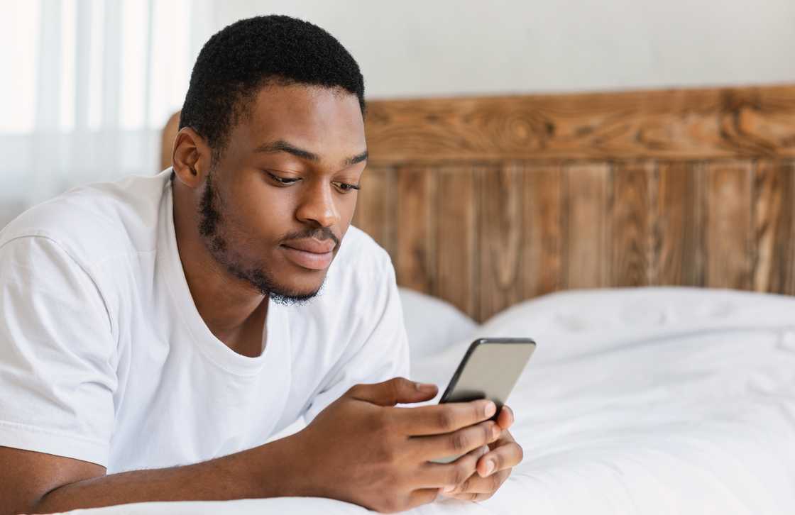 A man using mobile phone while lying in bed A man using mobile phone while lying in bed