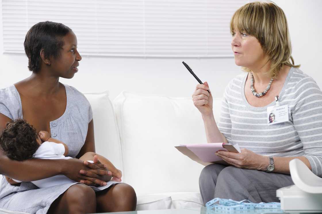 A healthcare worker advising a nursing mother