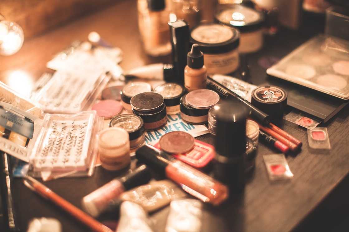 Assorted makeup products and brushes on a dressing table.