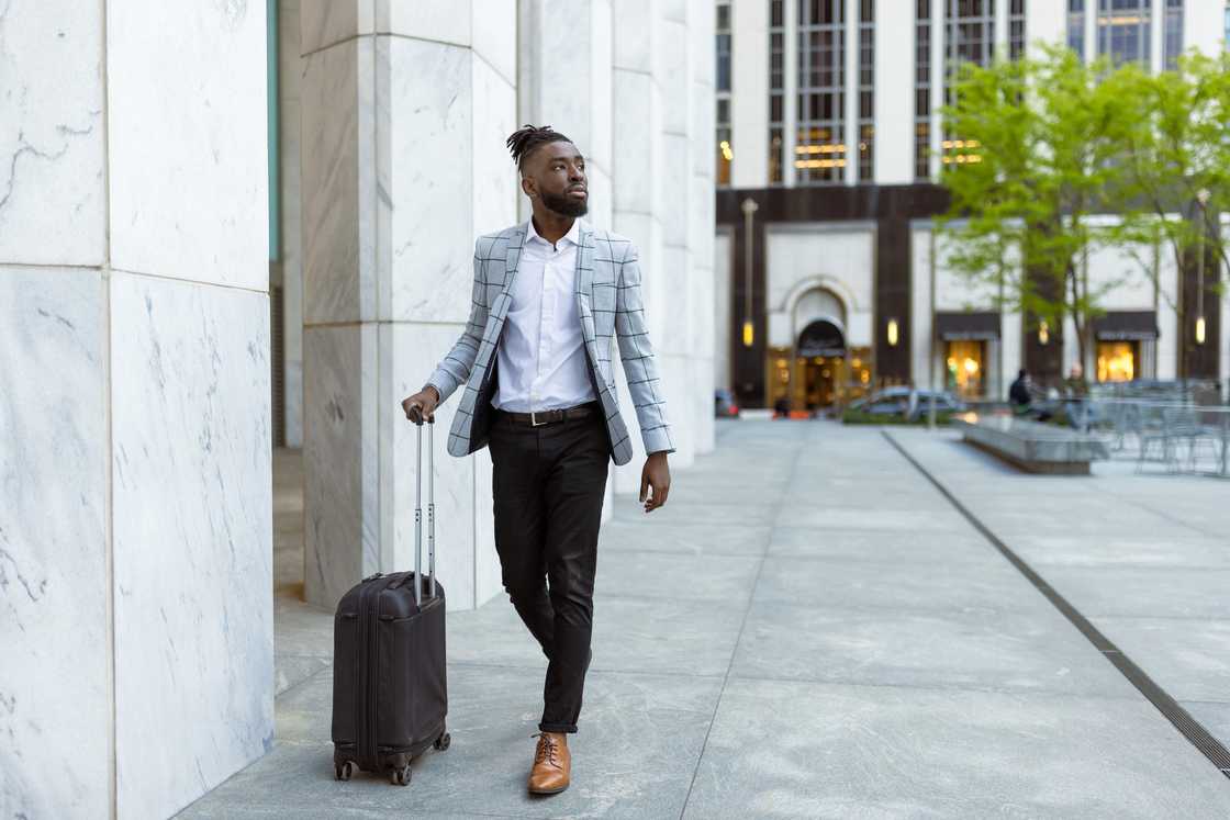 A businessman with luggage walking outside in an urban environment