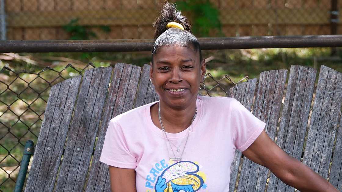 Simone Biles' birth mom Shanon smiles while sitting on wooden chairs. Simone Biles' birth mom Shanon smiles while sitting on wooden chairs.