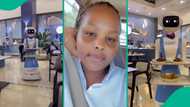 Nigerian lady sits as robot waiter delivers her meal in a restaurant effortlessly