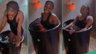 Lady dips herself inside big drum filled with cold water after she could not go to swimming pool