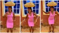 Groundnut seller in pink gown dances with large tray on her head, smiles happily in stunning video