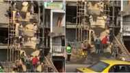 Construction workers have fun, sing in unison as they shovel cement to upper floor of 2-storey building