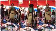 Lady who sells second hand clothes in market sings and shakes waist to attract customer in video