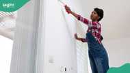Young lady paints a house on Banana Island with stunning colours and designs, smiles as she works