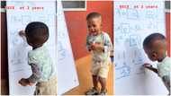 Kid, 2, solves JSS 3 maths questions on whiteboard, writes answers with confidence, dances in joy