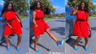 Gorgeous lady in red dress, blue shoes dances stylishly on road, video captures attention