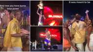 Lady shows off fine Burna Boy jacket she got at an event in viral video, friends take pictures with her