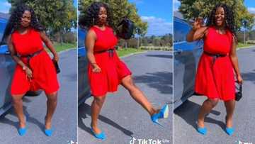 Gorgeous lady in red dress, blue shoes dances stylishly on road, video captures attention