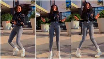 Slender lady with long legs dances in front of big mansion, twists her flexible body like robot in video
