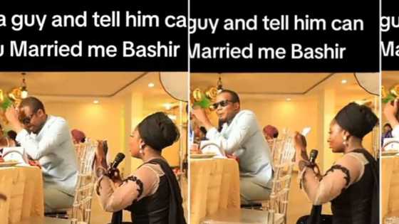 Lady proposes to man at another couple's wedding, kneels down while holding microphone, he agrees in video
